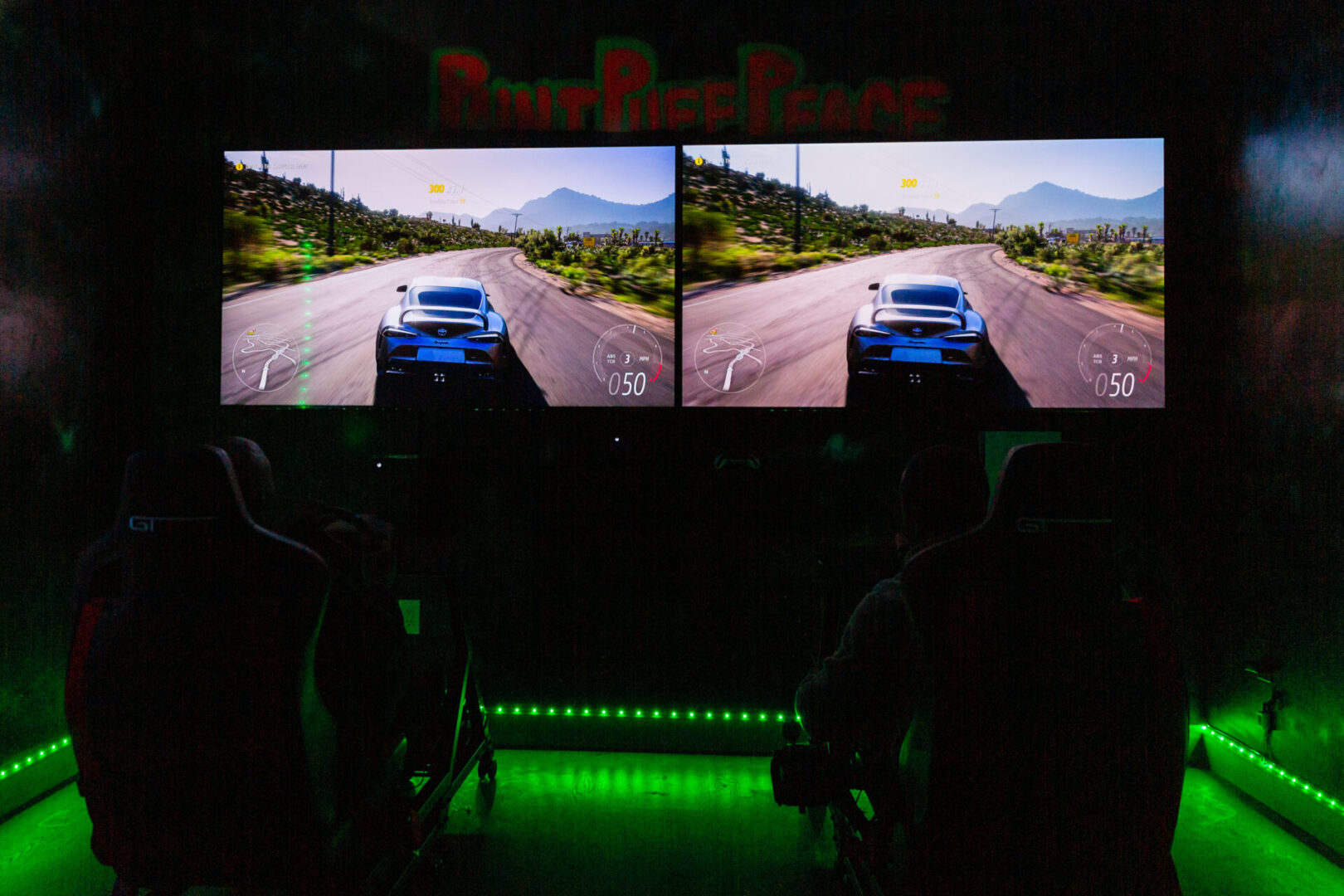 two screens of a racing video game in a dark room